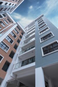 Modern mid-rise apartment buildings viewed from below against a blue sky.
