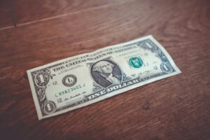 One-dollar bill lying flat on a wooden surface.