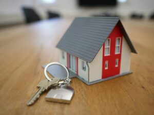 A small model house and a house key on a wooden table.